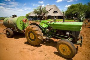 Image of a dusty tractor hitched to a water tanker on a dirt field