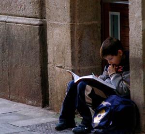 student with backpack sits and reads