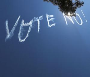 Picture of skywriting text "Vote No!" against clear blue sky