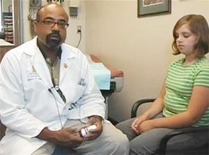 pediatrician holds medical device while sitting next to child