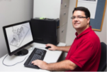 Photo of Kenneth Alfano next to a computer